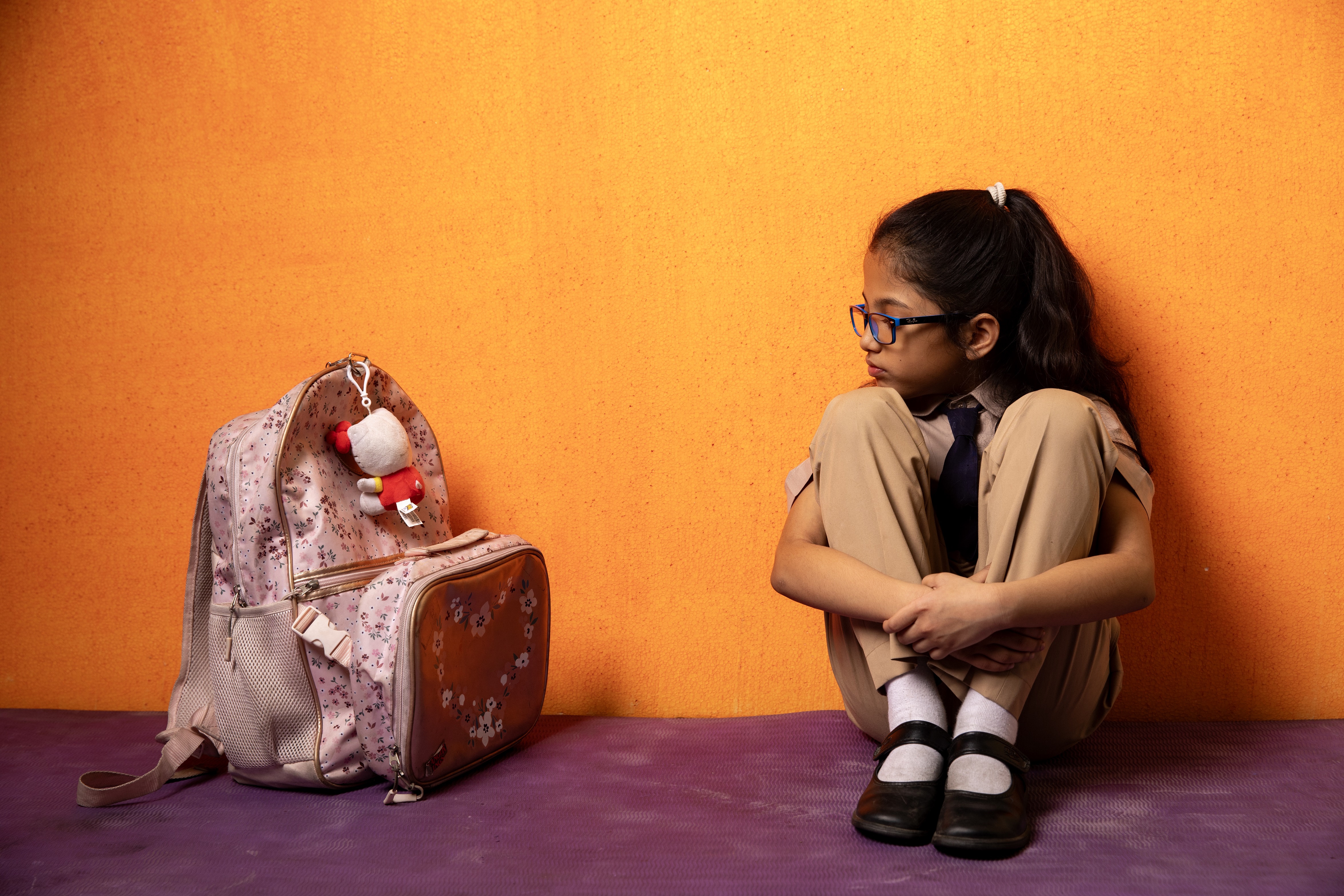 School student sitting beside their heavy school bag