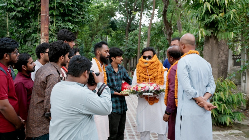 Students gathered around a student leader placing garlands on him.