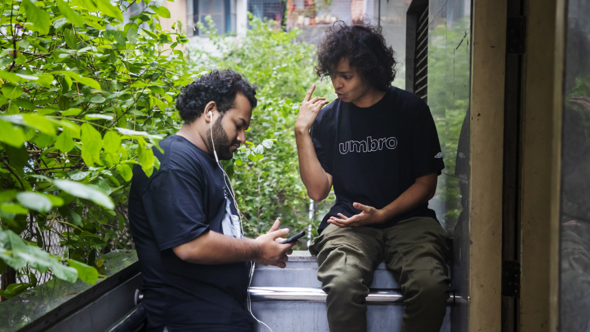 Two friends in one frame, one is talking and the other is listening to music