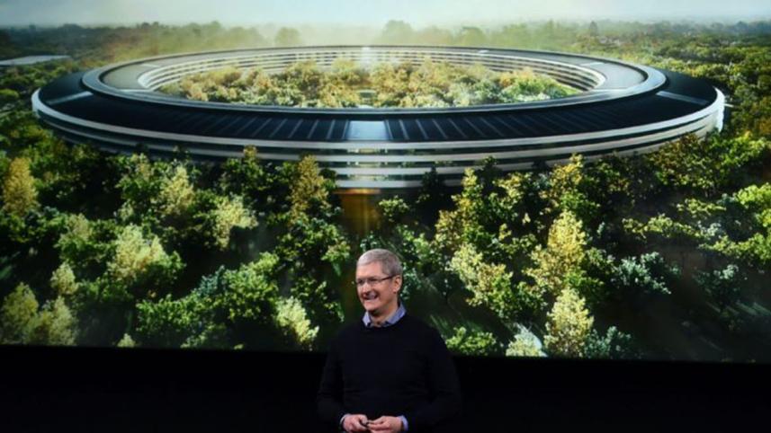 Apple CEO Tim Cook stands in front of a slide of the company's new campus
