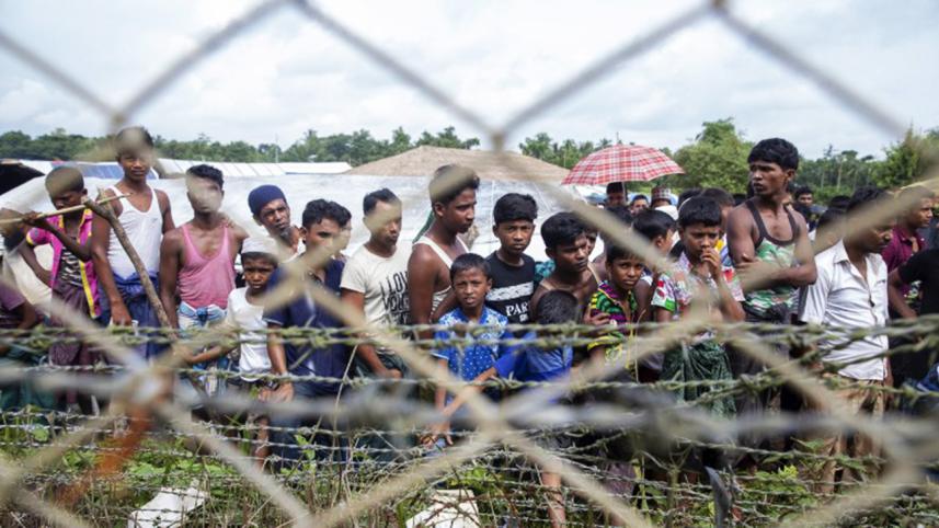 Rohingya refugees gather near the fence in the no man's land
