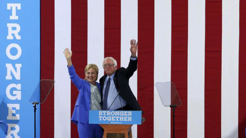Democratic US presidential candidate Hillary Clinton and Senator Bernie Sanders wave together during a campaign rally where Sanders endorsed Clinton.
