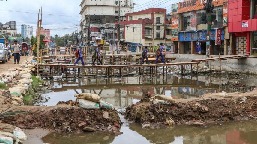 A group of students crosses an inundated portion of a road 