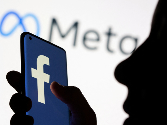 Woman holds smartphone with Facebook logo in front of a displayed logo for Meta in this illustration picture taken October 28, 2021. Photo: Reuters