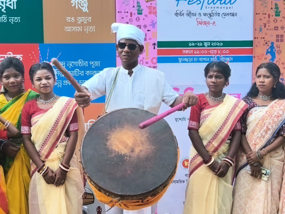 Dressed in traditional white clothing and a turban, Robi Munda plays the nagara at the Harmony Festival