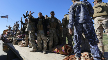 Iraqi security forces and Shiite fighters gesture