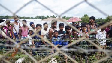 Rohingya refugees gather near the fence in the no man's land