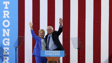 Democratic US presidential candidate Hillary Clinton and Senator Bernie Sanders wave together during a campaign rally where Sanders endorsed Clinton.